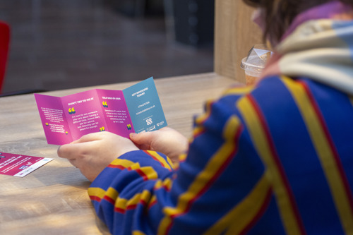 Image is of a member of the public reading a talking tip card.