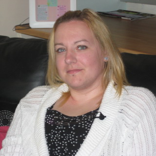 A young woman with blonde hair, wearing a white cardigan