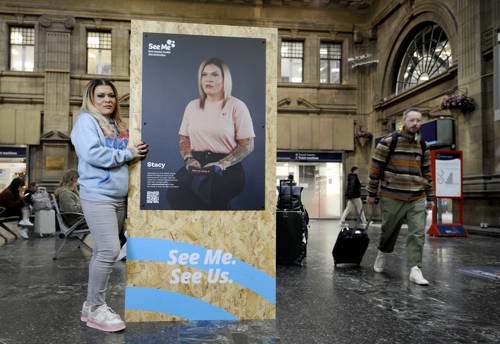 Stacy Pettiford, a young woman wearing jeans and a hoodie, stands with a display stand at See Me's The Guard campaign launch.